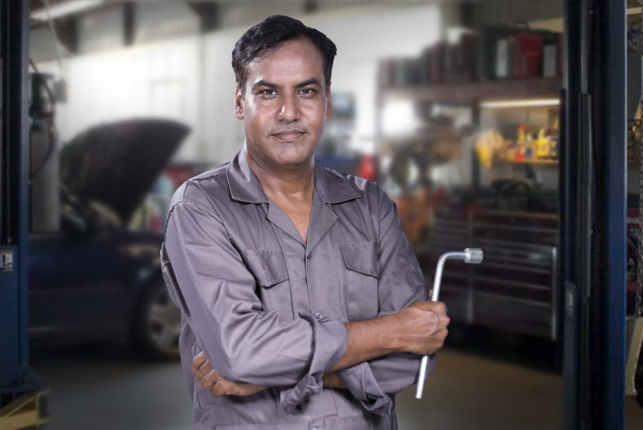 Friendly automotive mechanic holding a tire